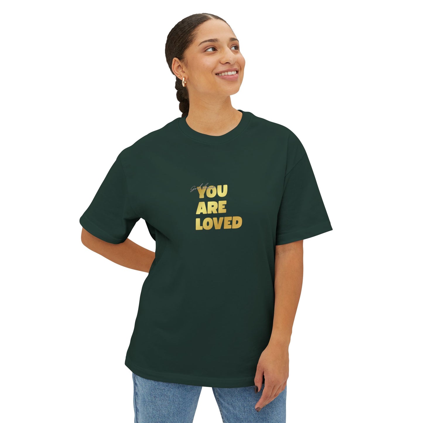Woman wearing forest green oversized boxy t-shirt adorned with 'You Are Loved' text in gold on chest.