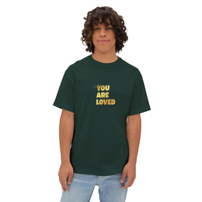 Man wearing forest green oversized boxy t-shirt adorned with 'You Are Loved' text in gold on chest.