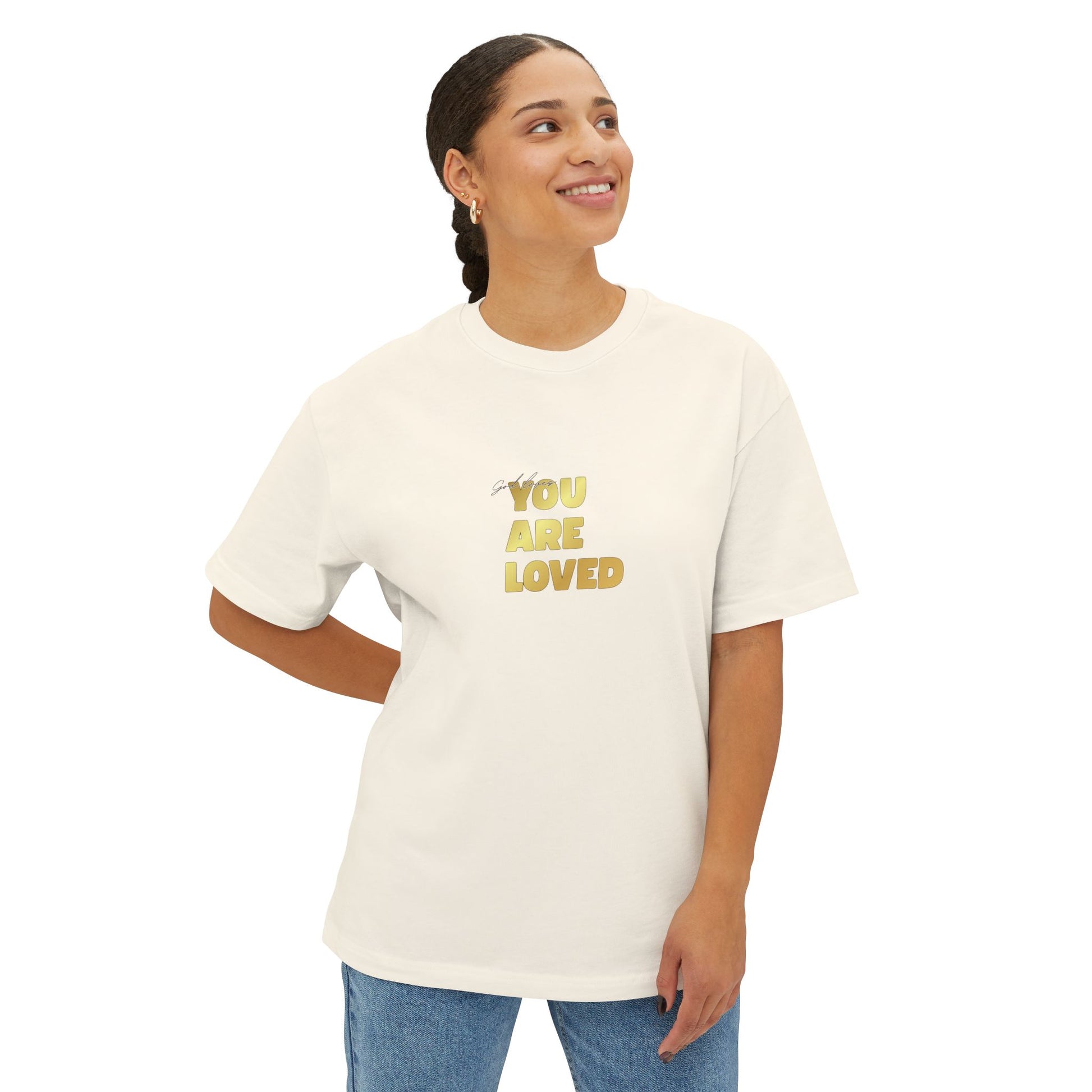 Woman wearing natural oversized boxy t-shirt adorned with 'You Are Loved' text in gold on chest.