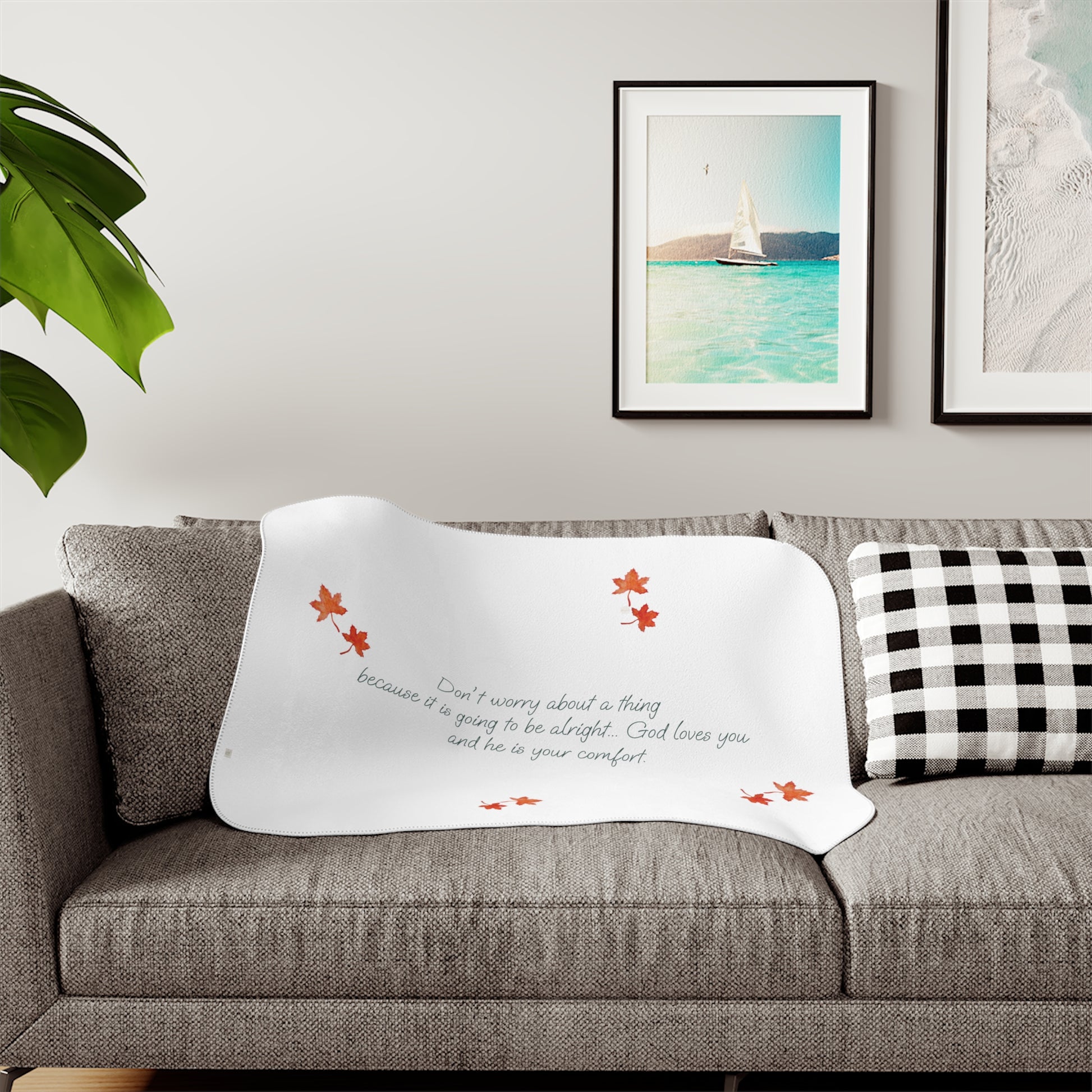White 30"x40" blanket with inspirational text, maple leaves pattern and eKuumeArt logo – displayed on a grey sofa in a living room setting.