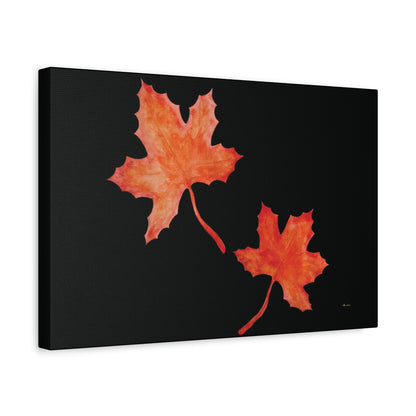 Black stretched canvas adorned with two orange-red watercolour maple leaves and eKuumeArt logo – angled view.