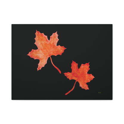 Black stretched canvas adorned with two orange-red watercolour maple leaves and eKuumeArt logo – front view.