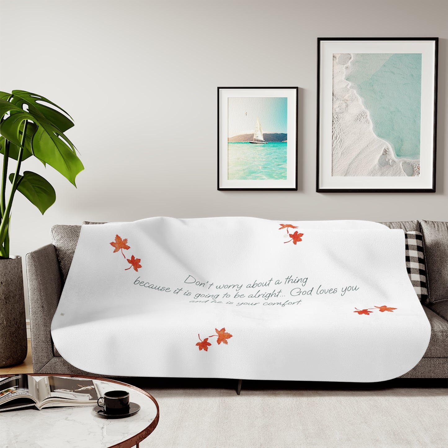 White 60"x80" blanket with inspirational text, maple leaves pattern and eKuumeArt logo – displayed on a grey sofa in a living room setting.