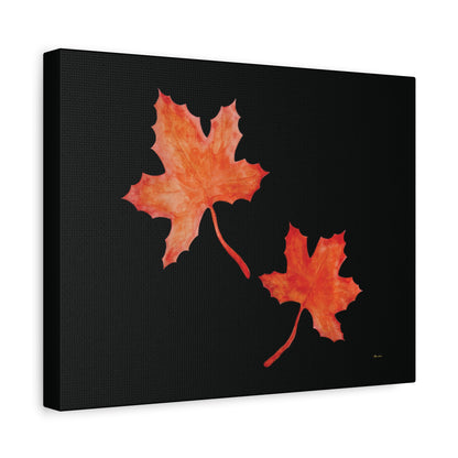 Black stretched canvas adorned with two orange-red watercolour maple leaves and eKuumeArt logo – angled view.