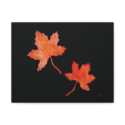 Black stretched canvas adorned with two orange-red watercolour maple leaves and eKuumeArt logo – front view.