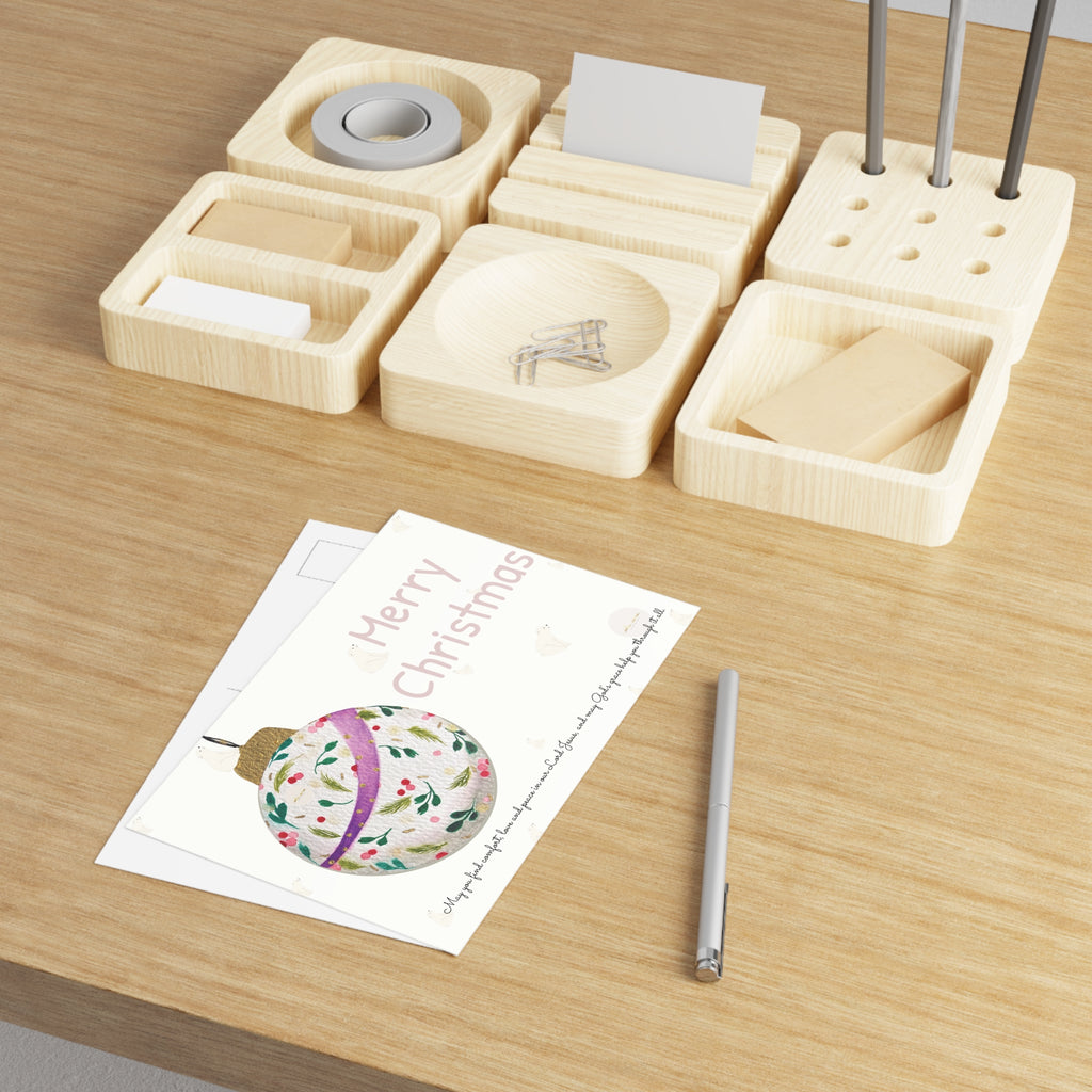 Christmas postcard with watercolour Christmas ball and prayer text  – displayed on wooden desk with wooden organizer with compartments and pen.