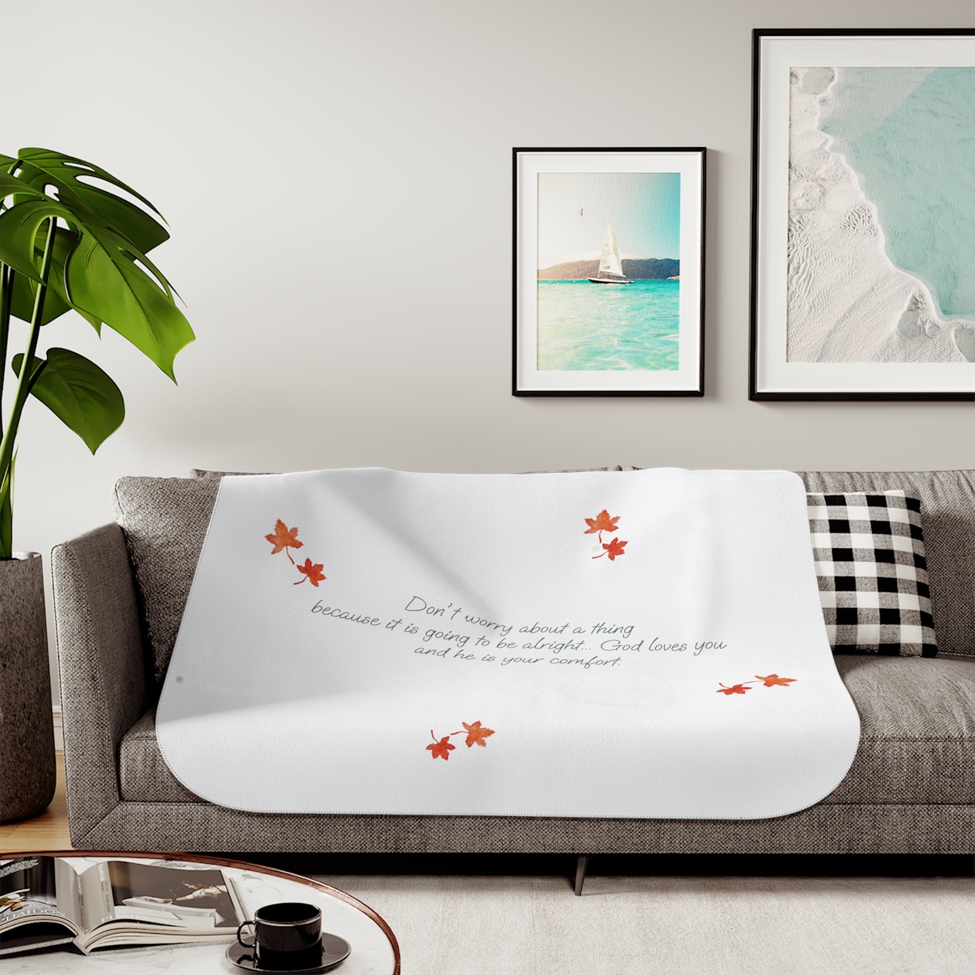 White 50"x60" blanket with inspirational text, maple leaves pattern and eKuumeArt logo – displayed on a grey sofa in a living room setting.