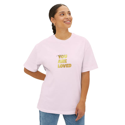 Woman wearing soft pink oversized boxy t-shirt adorned with 'You Are Loved' text in gold on chest.