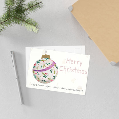 Christmas postcard with watercolour Christmas ball and prayer text – displayed on concrete-like surface styled with a pen, a little Christmas greenery and small box.