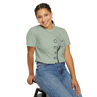 Woman seated on stool wearing bay tshirt with hand-drawn tree, 'Omemma' text and eKuumeArt logo on torso.