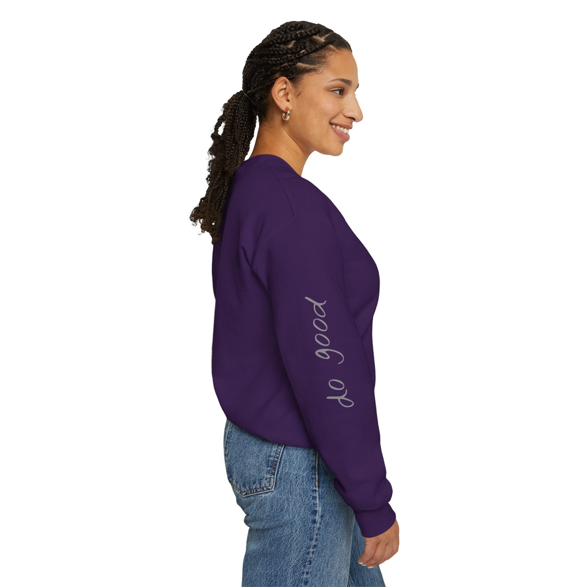 Woman wearing purple crewneck sweater with "be good, do good" on sleeves - right side view