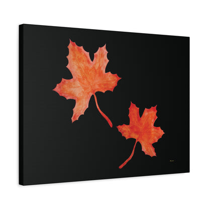 Black stretched canvas adorned with two orange-red watercolour maple leaves and eKuumeArt logo – angled view.