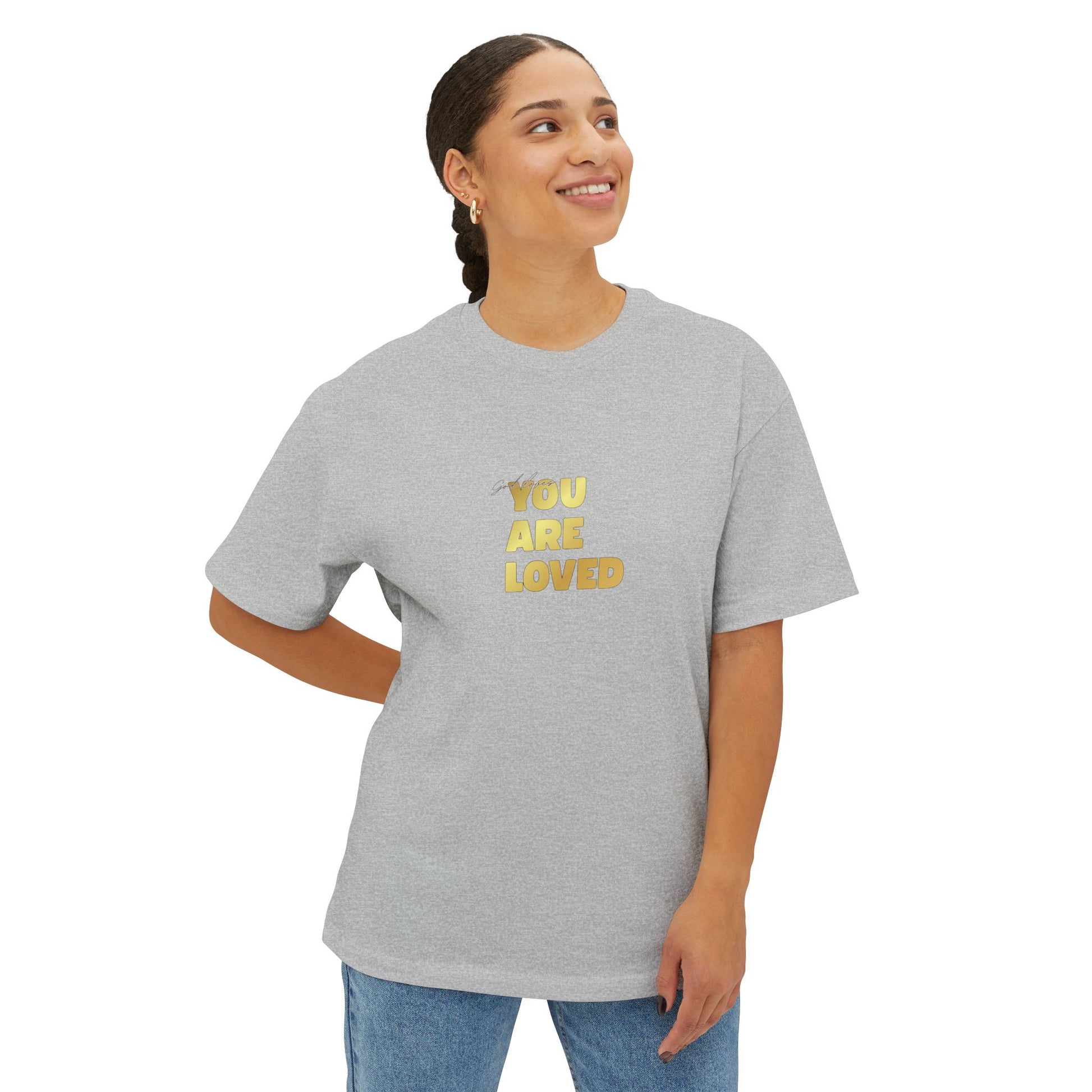 Woman wearing athletic heather oversized boxy t-shirt adorned with 'You Are Loved' text in gold on chest.