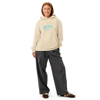 Woman wearing sandshell hoodie with 'I can't but God can' text on chest.