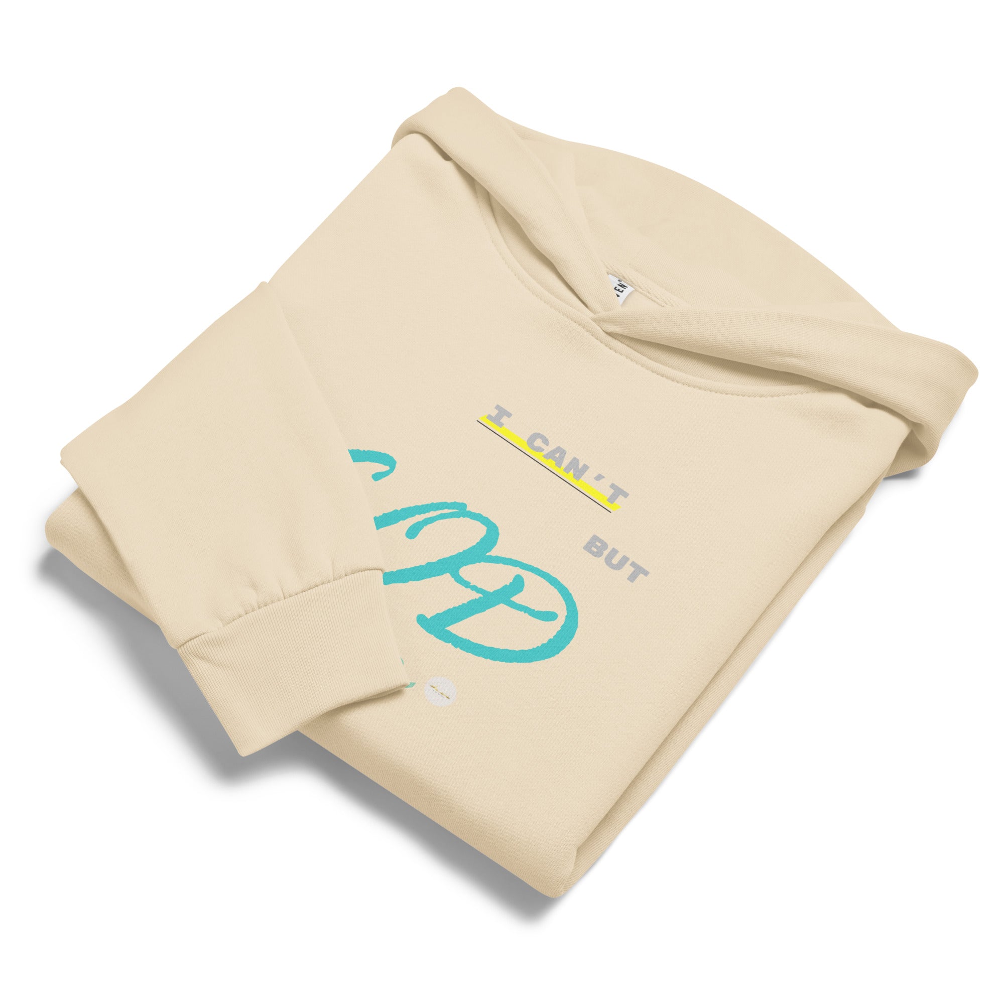 Sandshell hoodie, folded displaying 'I can't but God can' text and eKuumeArt logo on chest – one sleeve fold covering part of text.