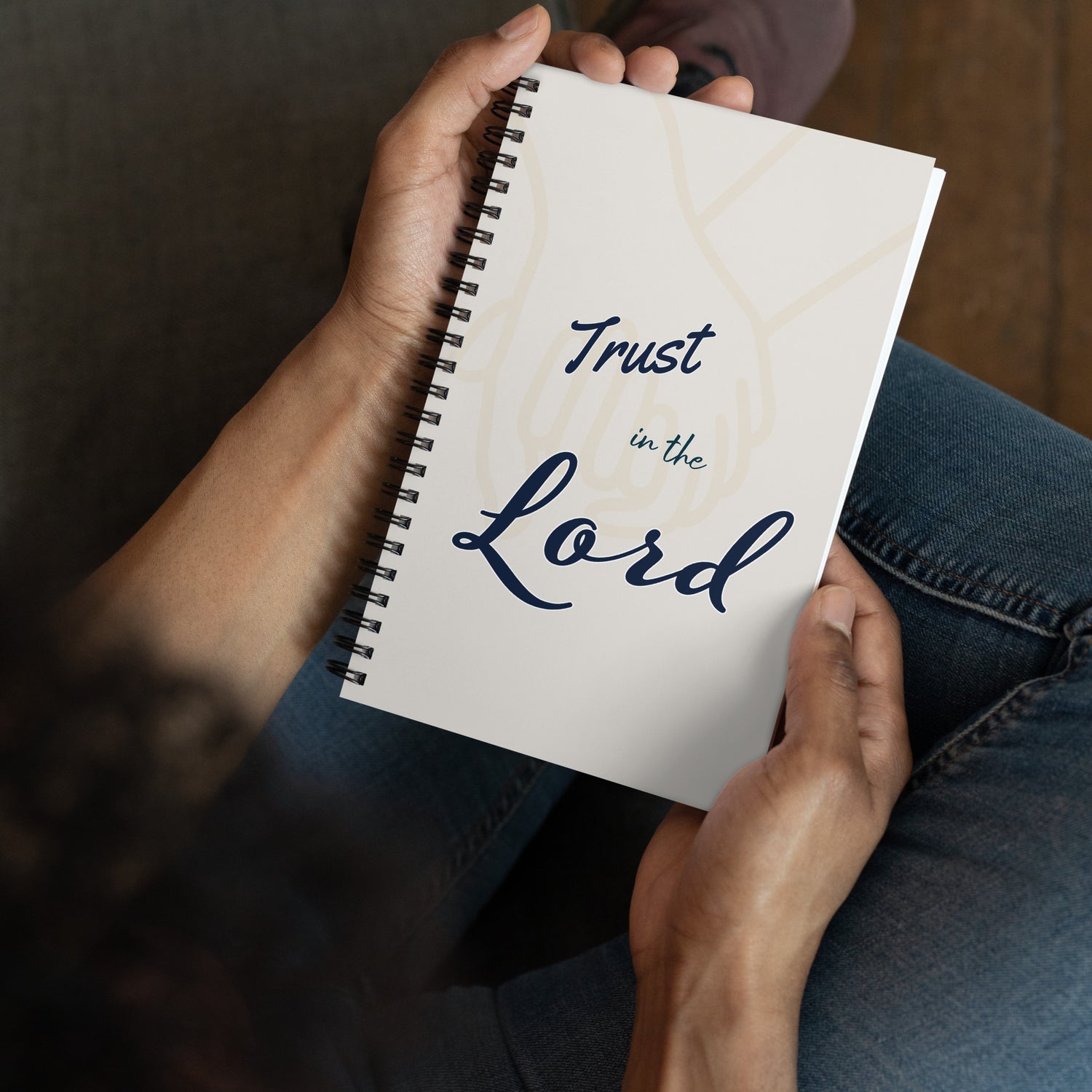 Person holding the spiral journal/notebook with 'Trust in the Lord' text on the cover.