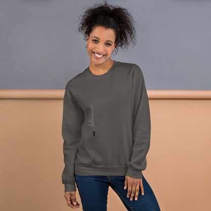 Woman wearing charcoal sweater with 'Believe' handwritten text and eKuumeArt logo on torso – front view, featuring a grey and brown room setting.