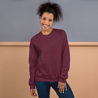 Woman wearing maroon sweater with 'Believe' handwritten text and eKuumeArt logo on torso – front view, featuring a grey and brown room setting.