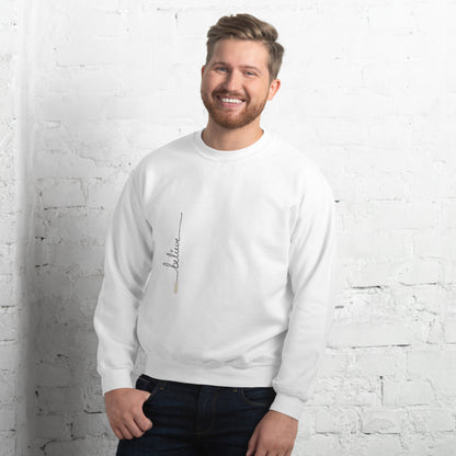 Man wearing white sweater with 'Believe' handwritten text and eKuumeArt logo on torso – angled view, featuring a white brick wall room setting.