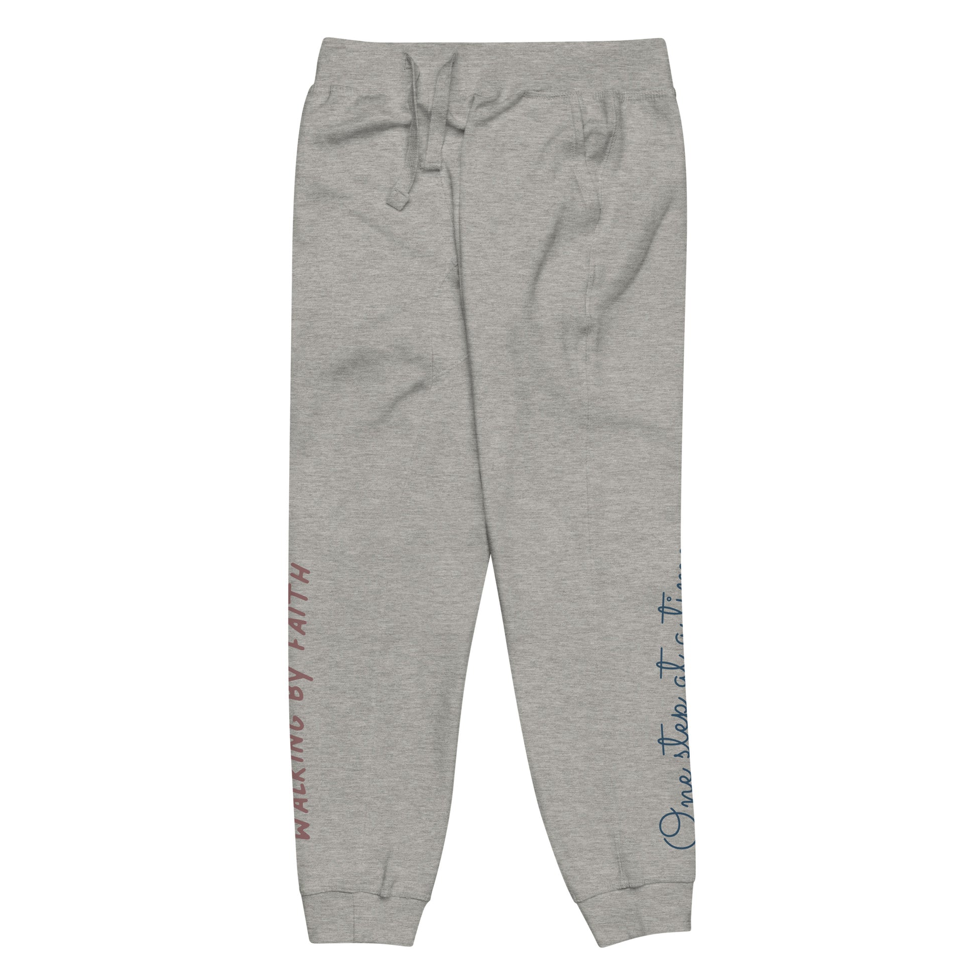 Carbon grey sweatpants adorned with 'Walking by faith' text and eKuumeArt logo on front right leg and glimpse of 'One step at a time' on back left leg – side view.