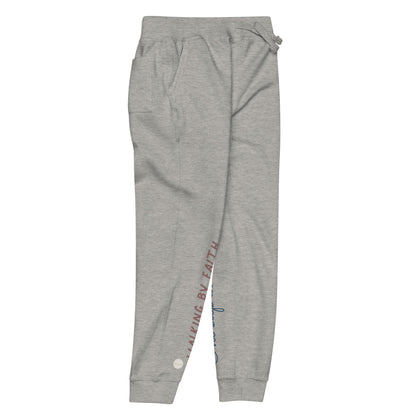 Carbon grey sweatpants adorned with 'Walking by faith' text and eKuumeArt logo on front right leg and glimpse of 'One step at a time' on back left leg – side view.