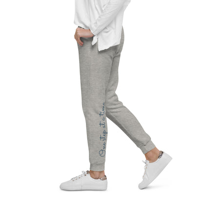 Person wearing carbon grey sweatpants with 'One step at a time' text and on back left leg – side view.