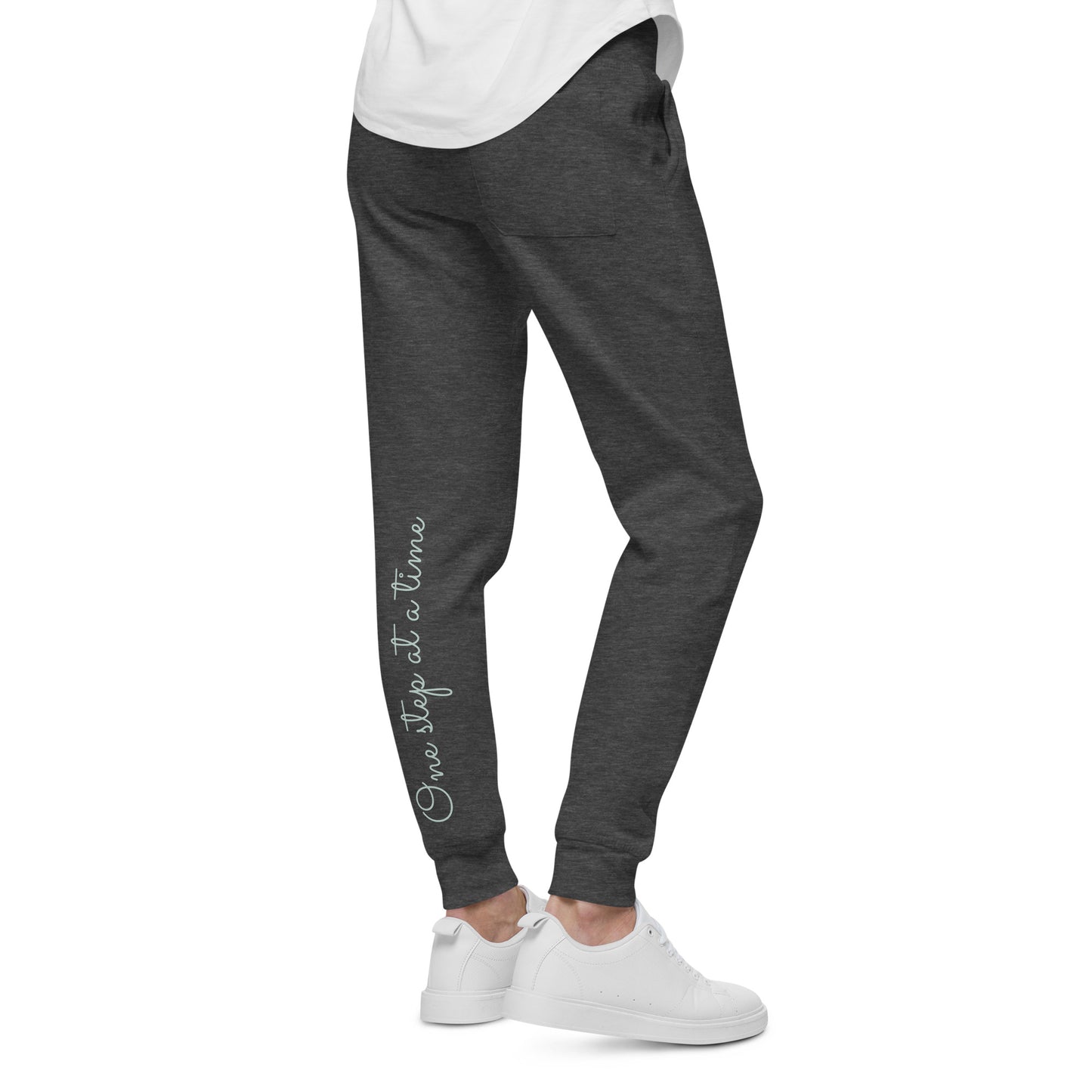 Person wearing charcoal heather sweatpants with 'One step at a time' text on back left leg – angled view.
