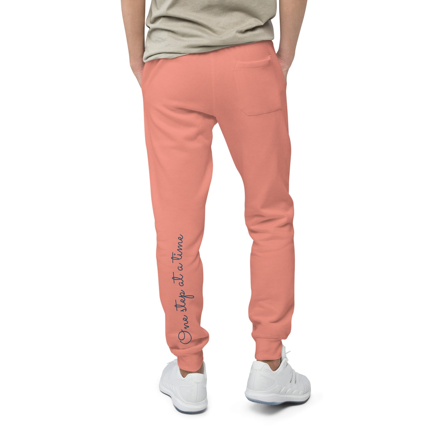 Person wearing dusty rose sweatpants with 'One step at a time' text on back left leg – back view.
