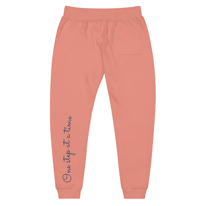 Dusty rose sweatpants adorned with 'One step at a time' text on back left leg.