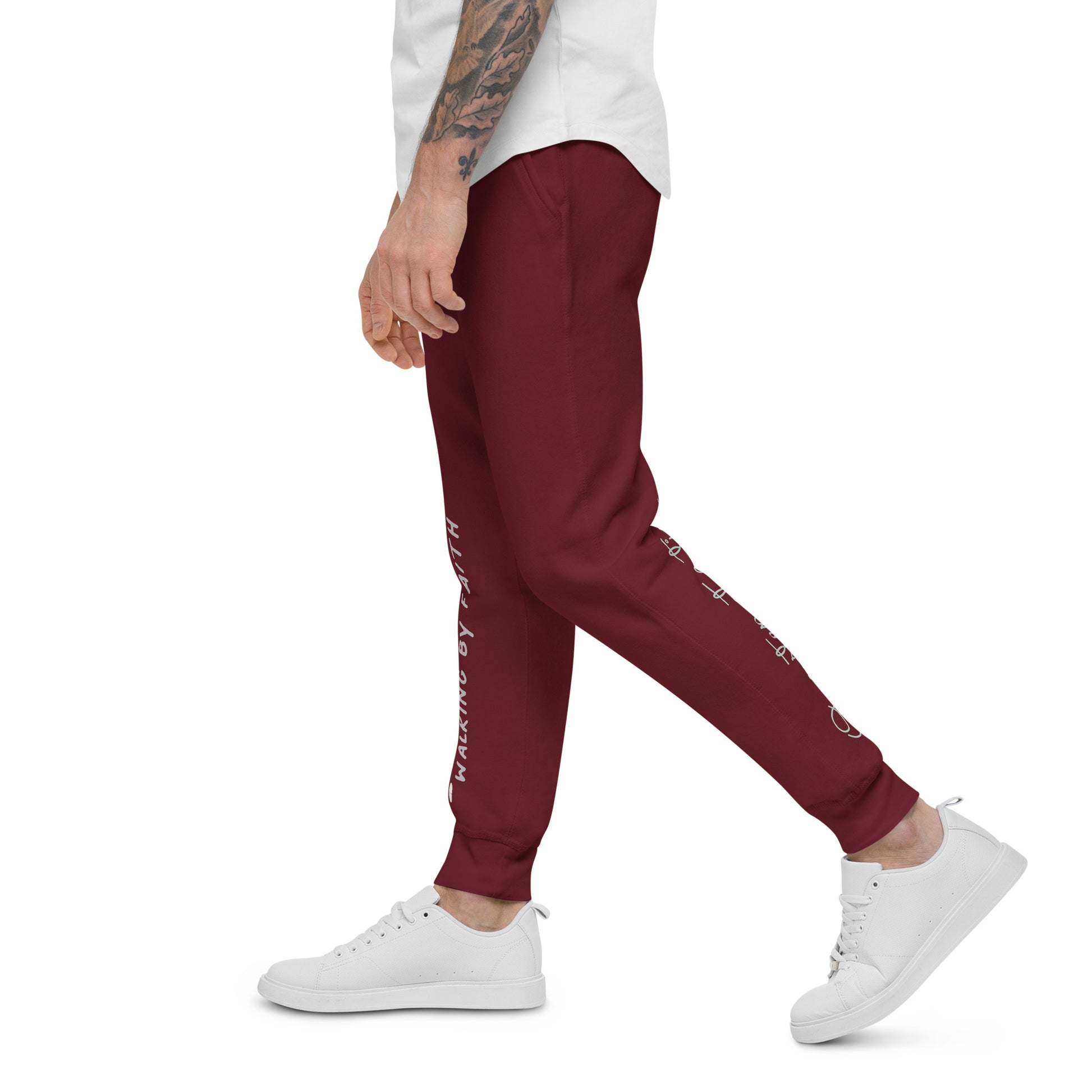 Person wearing maroon sweatpants with glimpses of faith-inspired texts on front right leg and back left leg – side view.