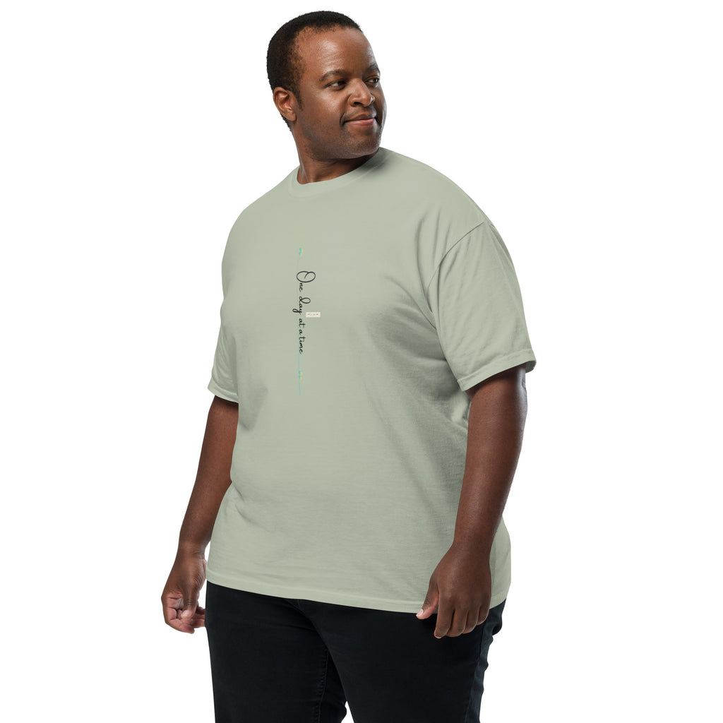 Man wearing bay tee with 'One day at a time' and eKuumeArt logo on middle chest – angled view.
