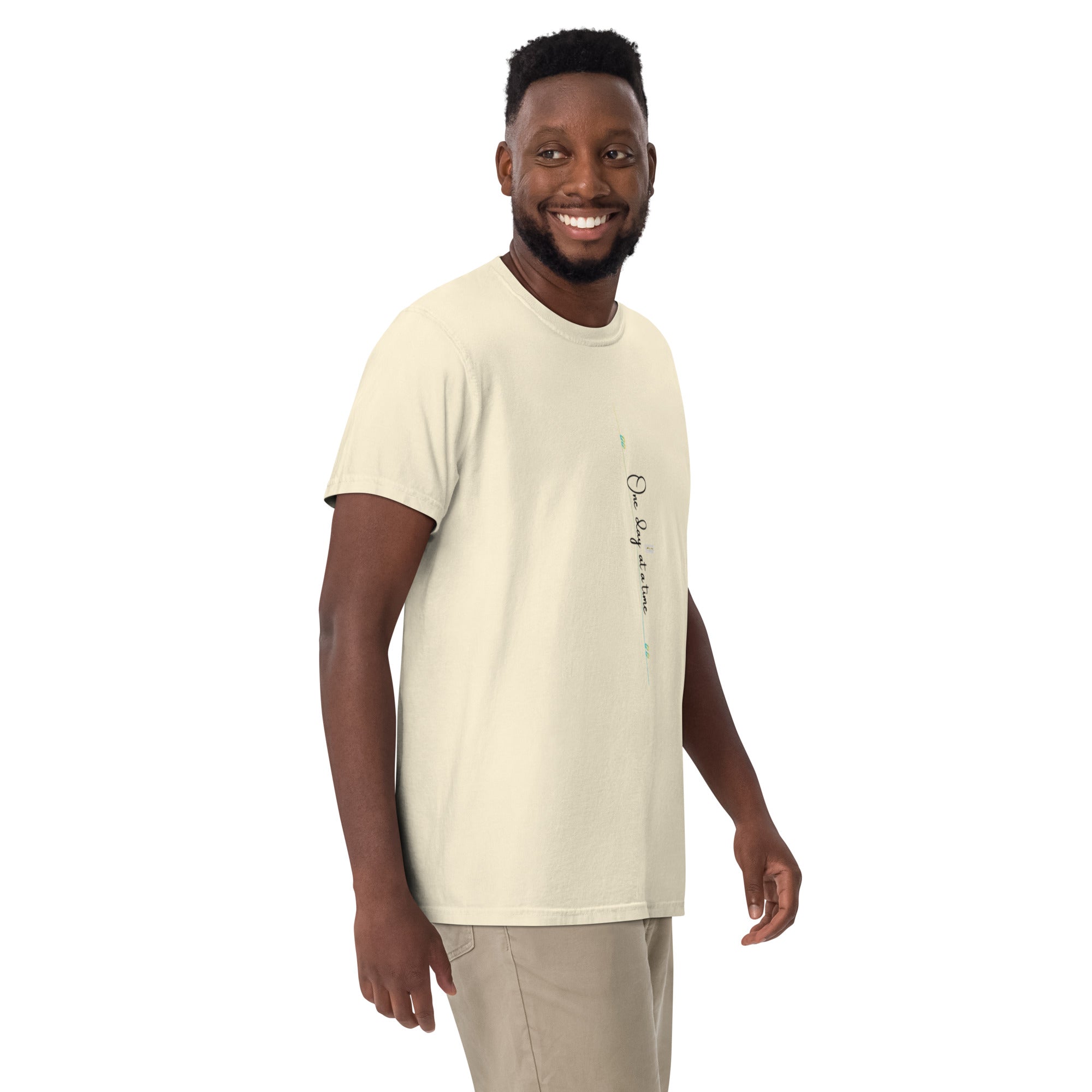 Man wearing ivory tee with 'One day at a time' and eKuumeArt logo on middle chest – angled view.