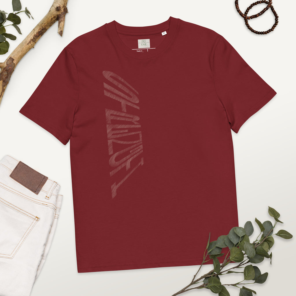 Burgundy organic cotton t-shirt with hand-drawn 'Strength' text and white jeans on a white surface with greenery | eKuumeArt.